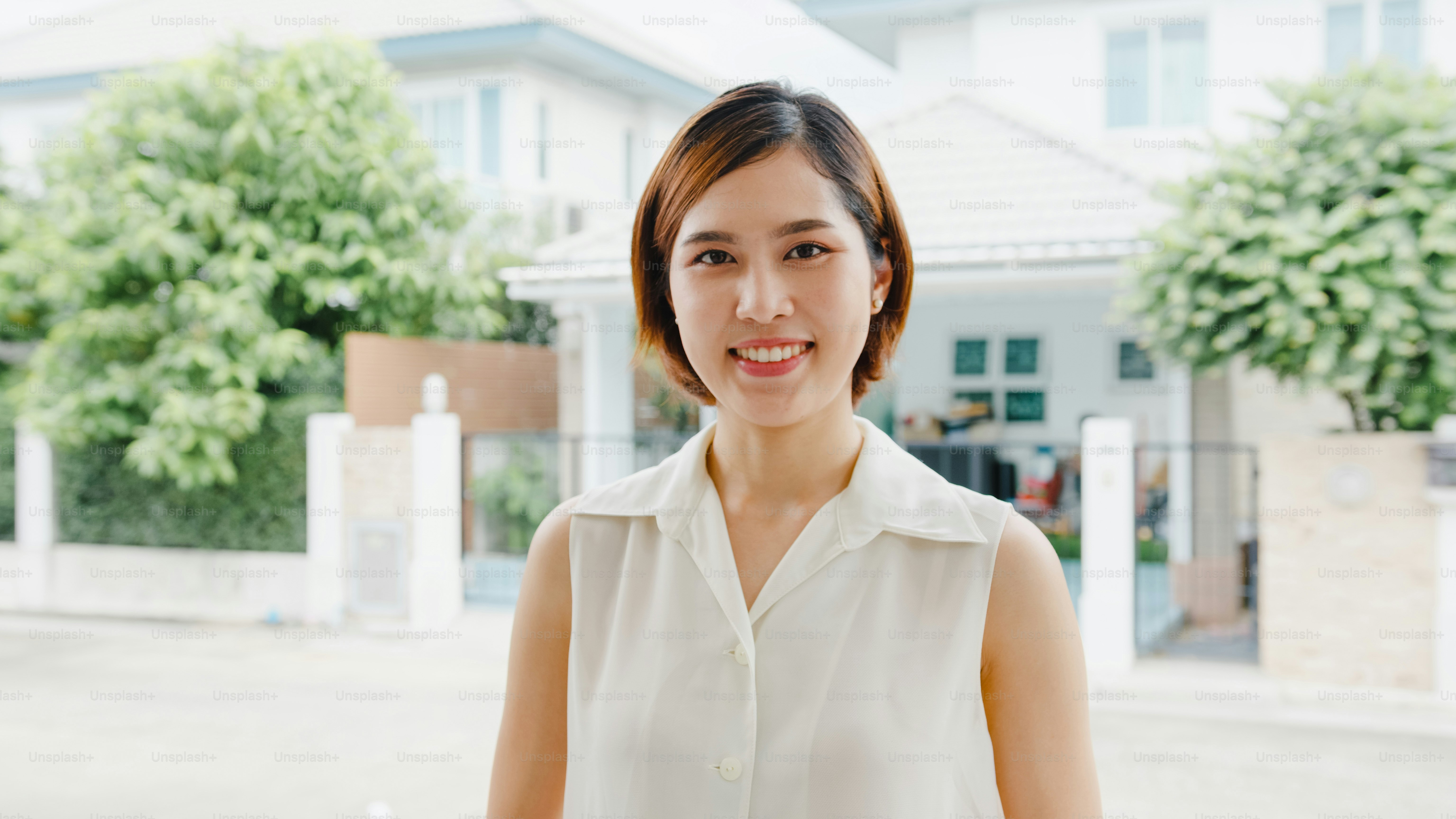 Happy young Asian female feeling happy smiling and looking to camera while relax on street in modern city. Lifestyle woman at outside house concept