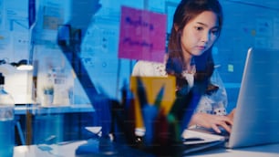 Mujeres asiáticas independientes que usan una computadora portátil para trabajar duro en la nueva oficina en casa normal. Sobrecarga de trabajo desde casa por la noche, trabajo remoto, autoaislamiento, distanciamiento social, cuarentena para la prevención del coronavirus.