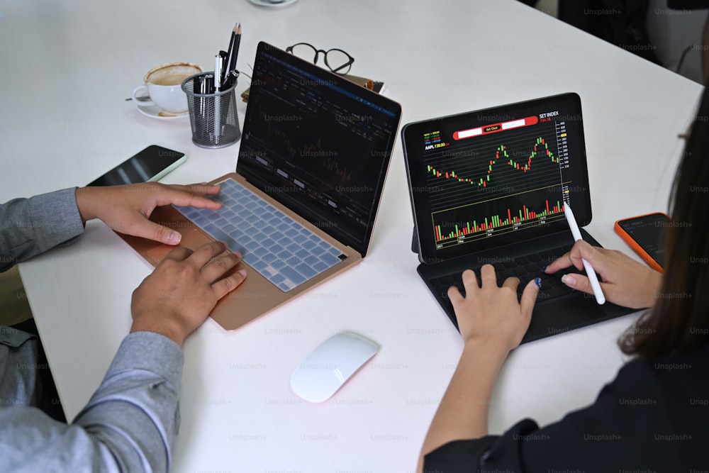 Business team analyzing graph of stock market financial and working together with computer tablet.