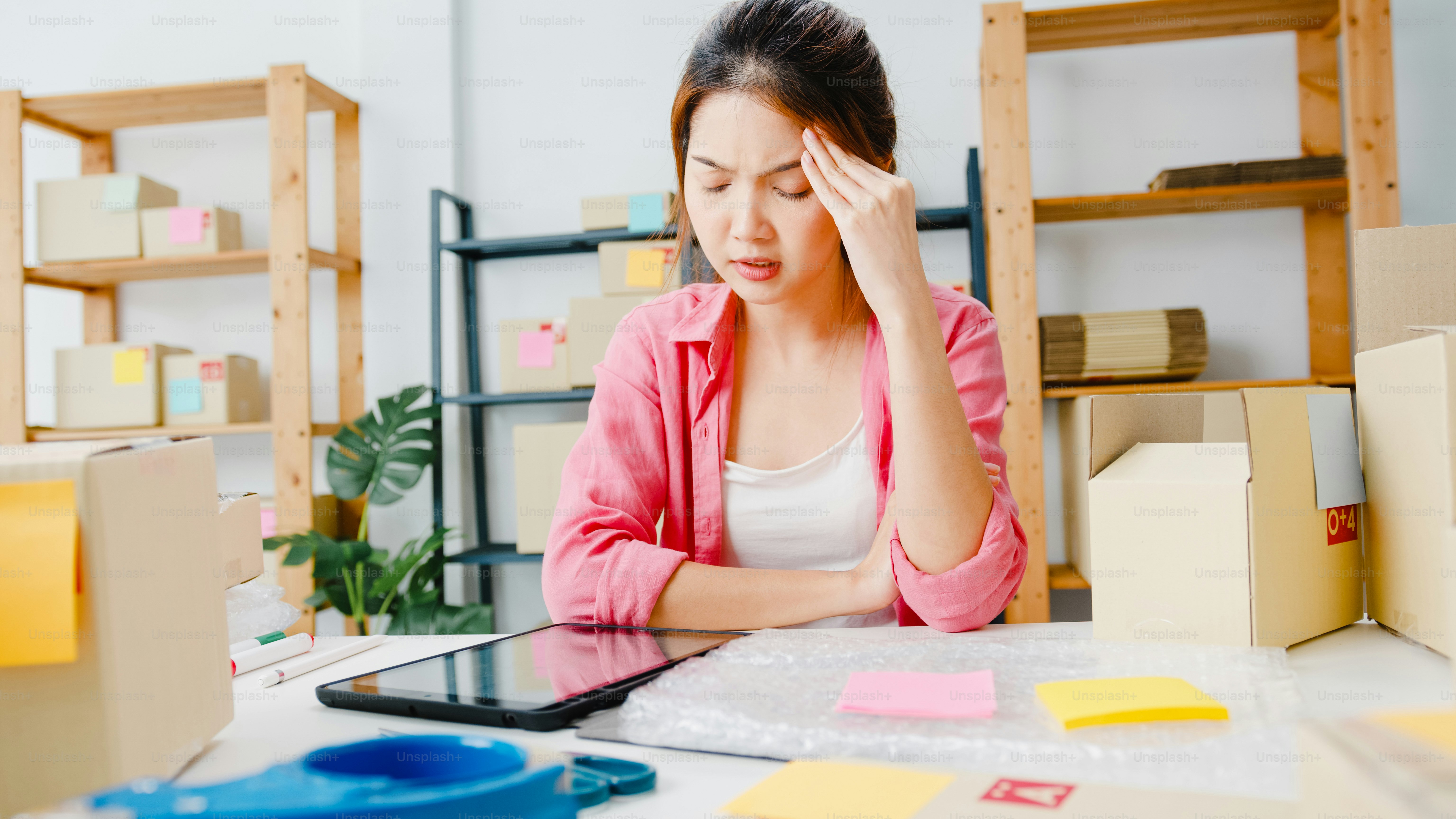 若いアジアの起業家のビジネスウーマンは、ホームオフィスでタブレットのハードワーク過負荷を使用して、在庫のある製品の発注書を確認します。中小企業の経営者、オンライン市場への配送、ライフスタイルのフリーランスのコンセプト。