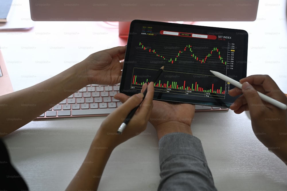 Geschäftsleute, die Aktienchartdaten auf einem digitalen Tablet analysieren.