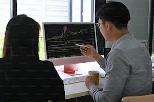 Two business people planning and analyzing graph on computer together.