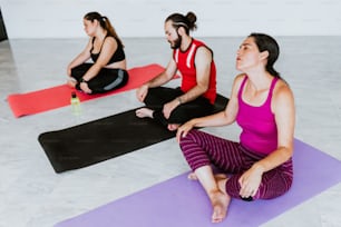 Group of young hispanic people sitting on mat while relaxing in yoga studio in Latin America