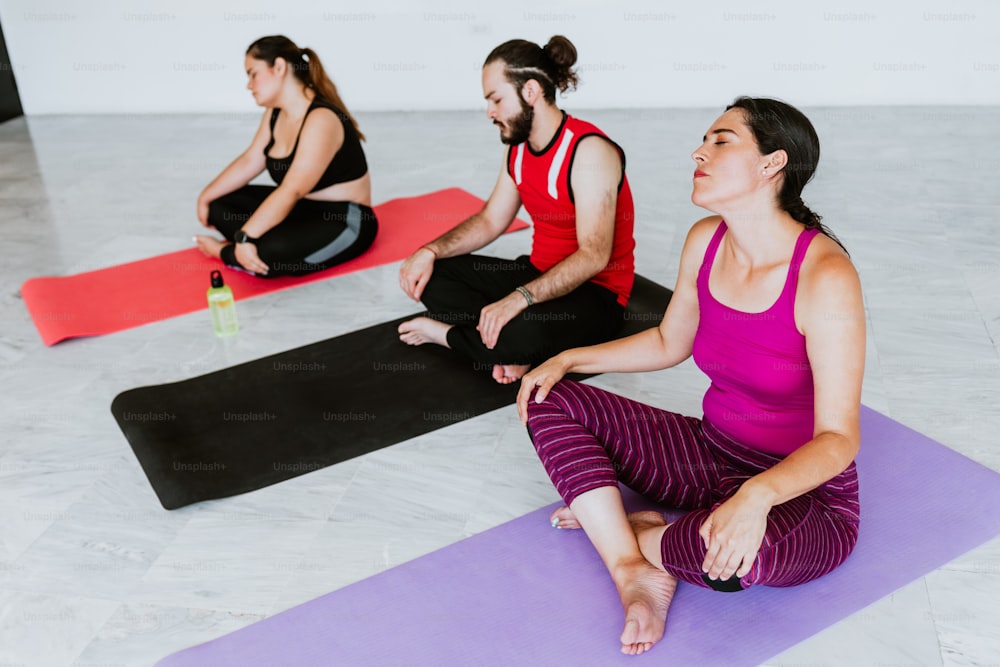 Group of young hispanic people sitting on mat while relaxing in yoga studio in Latin America