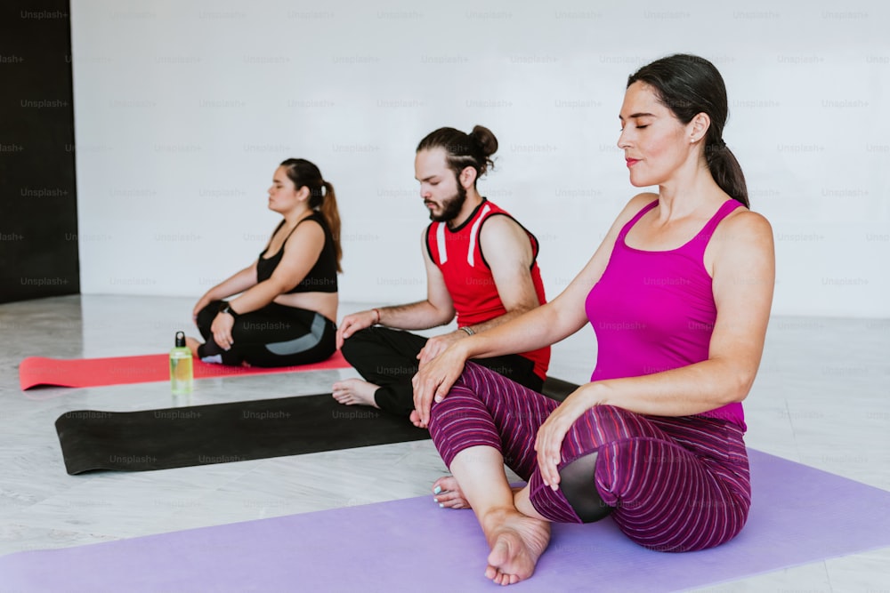 Grupo de jovens latinos meditando tranquilamente em estúdio de yoga na América Latina