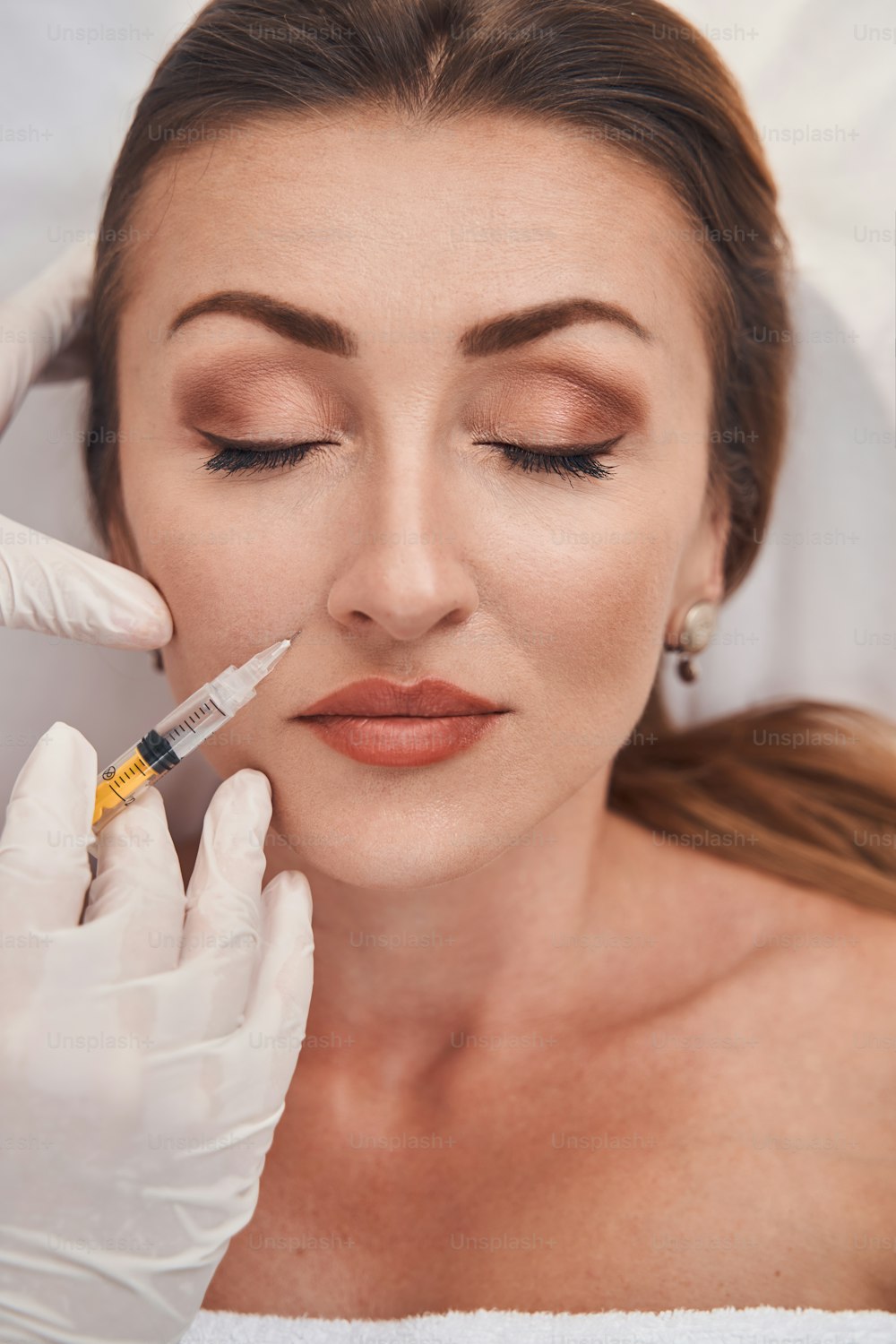 Top view close up of pretty female face while cosmetologist is doing mesotherapy with syringe