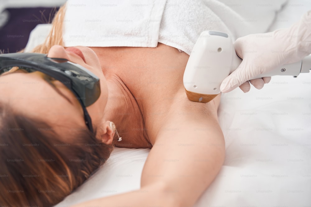 Foto Cosmetóloga profesional concentrada en gafas de seguridad realizando  una depilación láser en la pierna de una paciente femenina – Pelo Imagen en  Unsplash