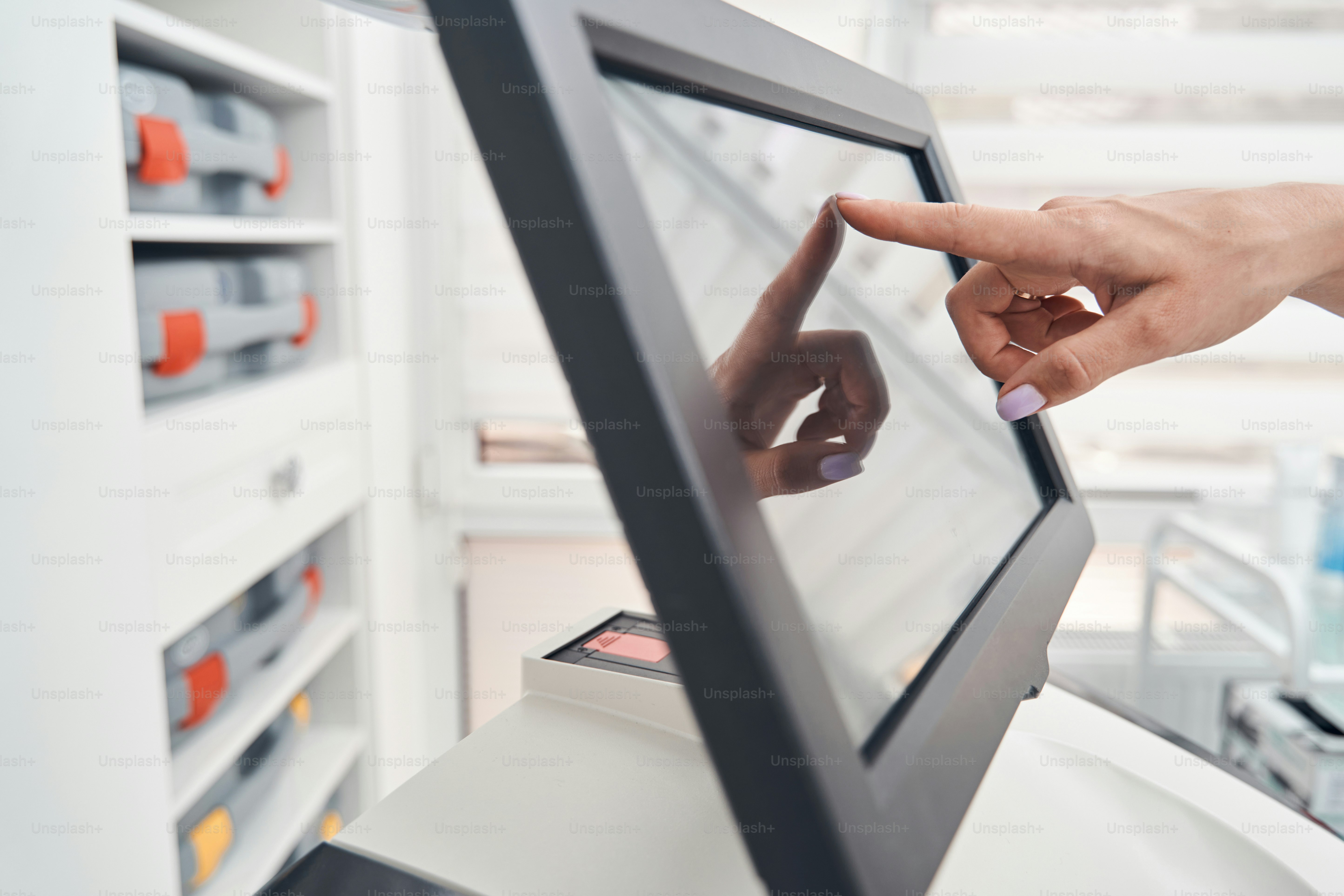 Primo piano testa ritagliata del dito femminile che preme sul touchscreen dell'attrezzatura digitale nel salone di bellezza