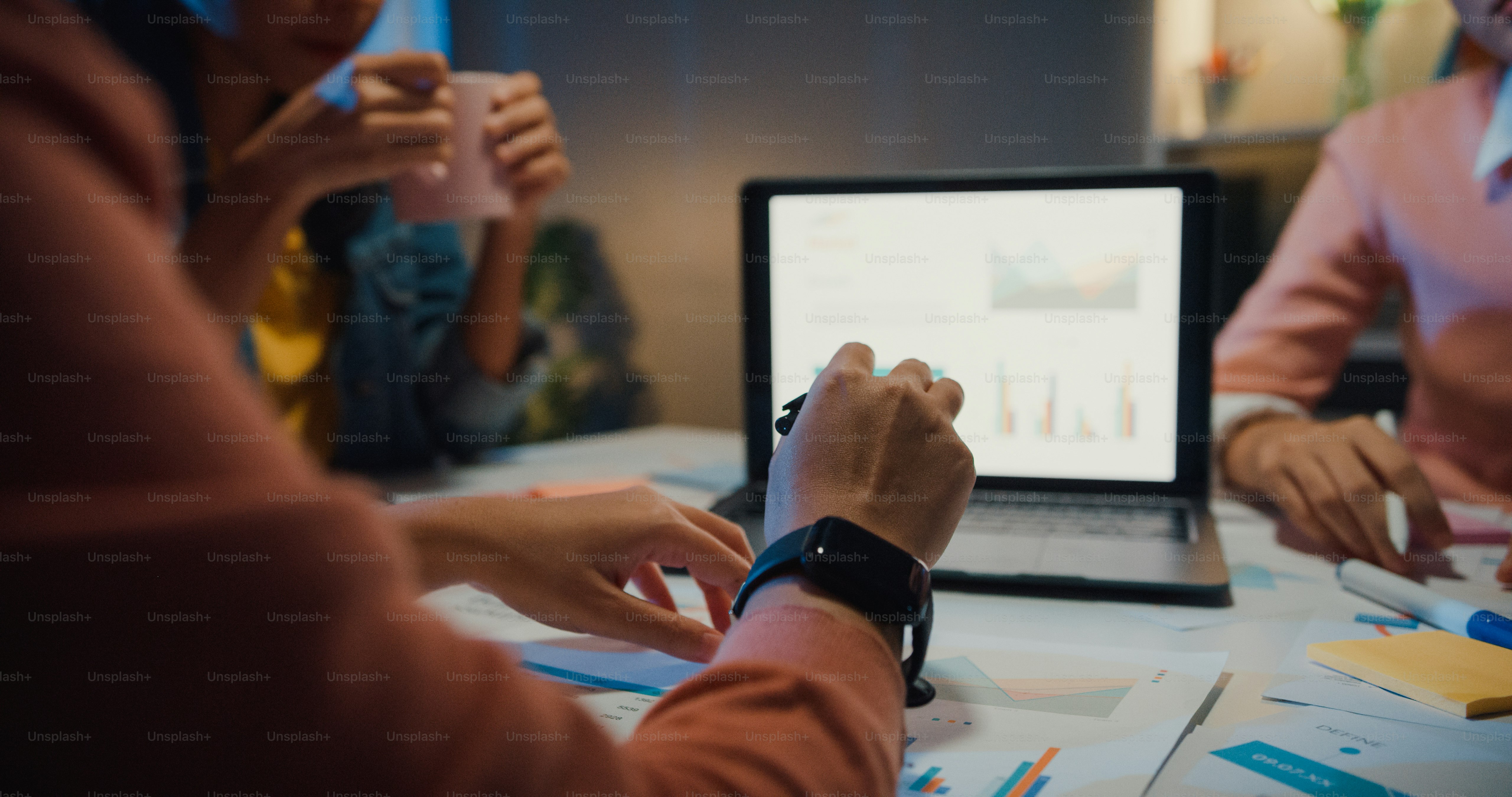 People working at a table with a laptop displaying charts in a workspace