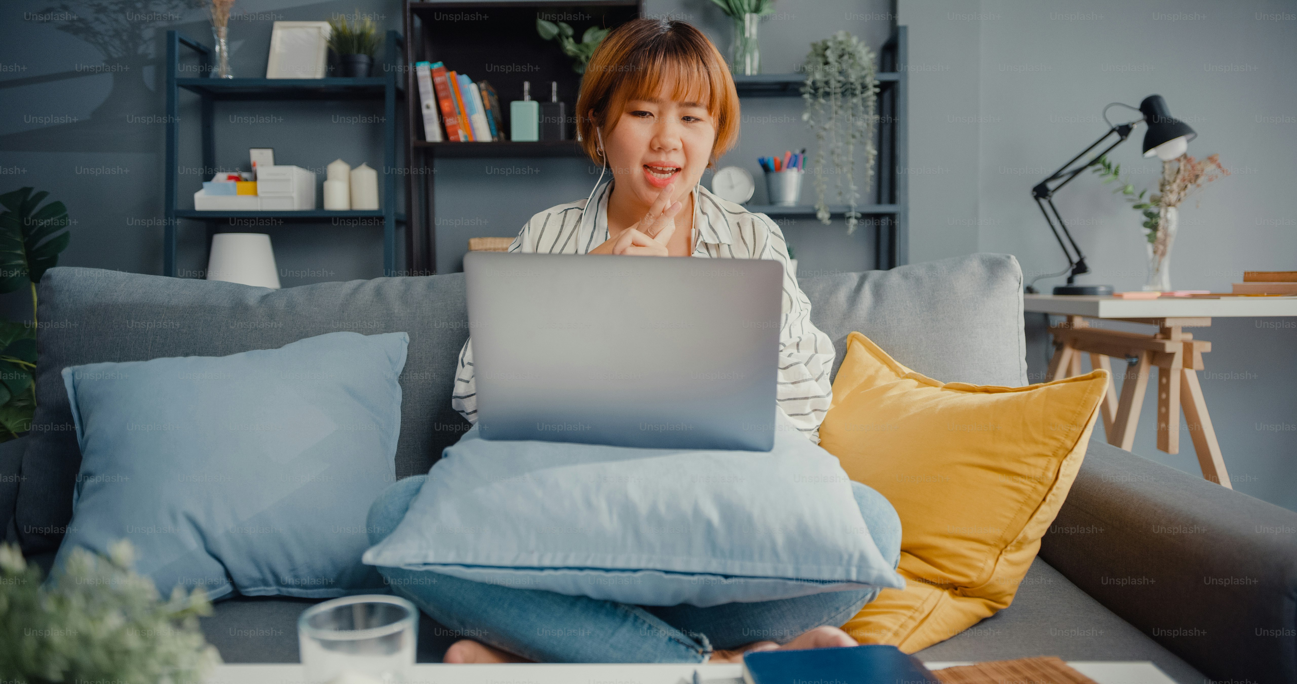 Asia businesswoman using laptop talk to colleagues about plan in video call while working from house at living room. Remotely at workplace, social distancing, quarantine for corona virus prevention.