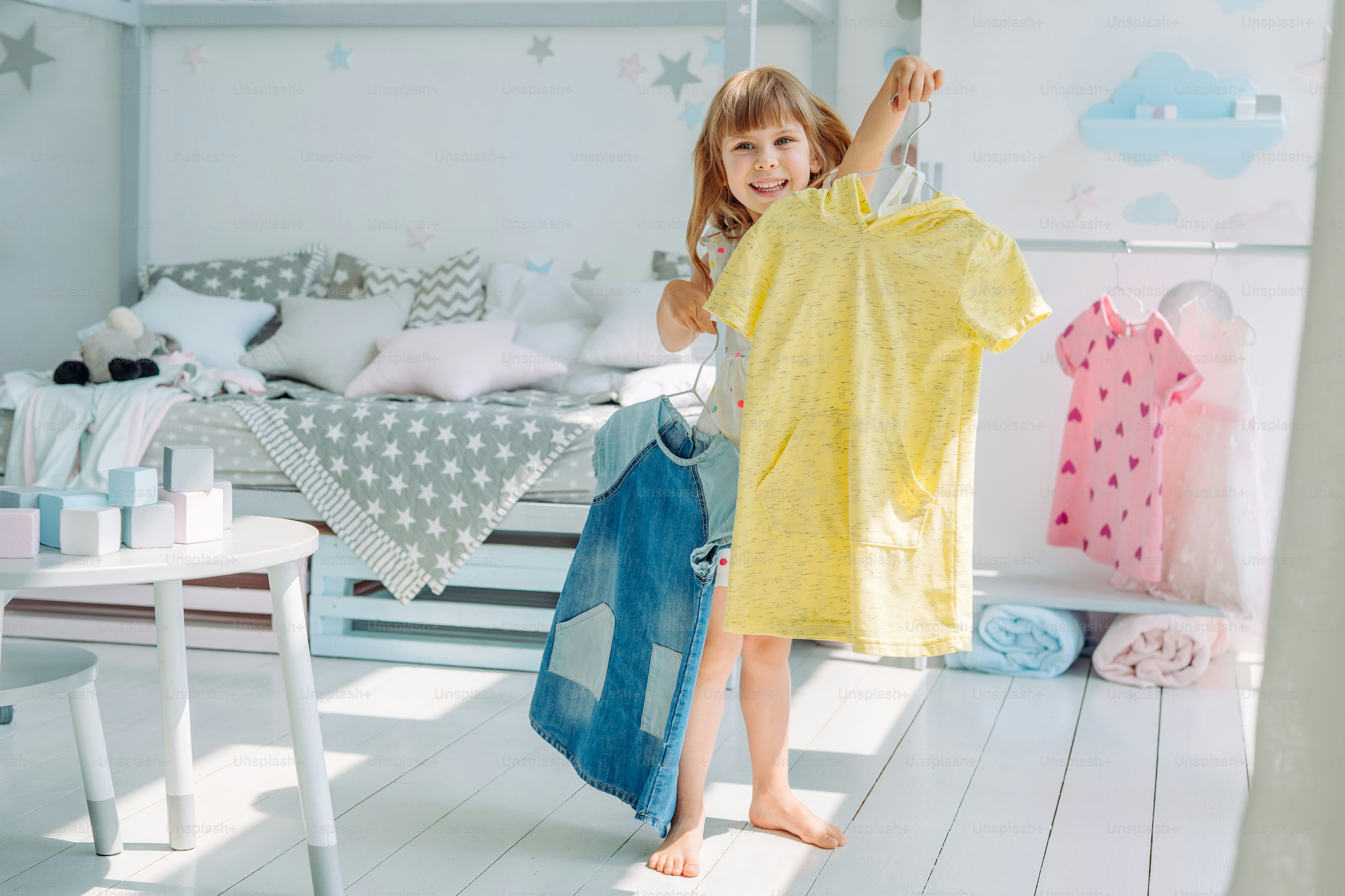 Beautiful little girl choosing a dress in the kids room. Selective focus.
