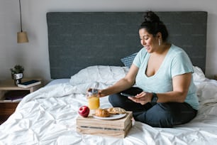 Joven latina de talla grande desayunando en su habitación en América Latina