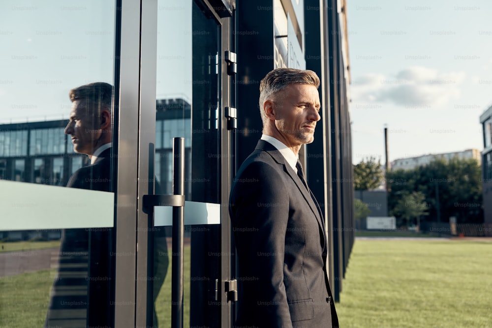 Confident mature businessman standing near office building outdoors