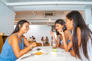 Group of Happy Asian woman girl friends sitting and talking together on the beach after skateboarding at skateboard park. Female friendship having fun outdoor activity lifestyle in summer vacation.