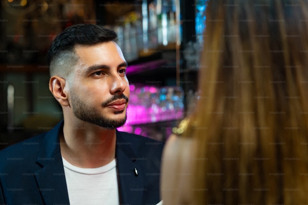 Mujer asiática de pie en la barra del bar y hablando con su novio bebiendo un cóctel alcohólico en un club nocturno. Mixólogo barman masculino que prepara una bebida alcohólica mezclada con decorar una copa de cóctel en la barra del bar