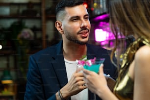 Donna asiatica in piedi al bancone del bar e che parla con il fidanzato bevendo cocktail alcolici in discoteca. Barista maschio mixologist che prepara bevanda alcolica mista con decorare il bicchiere da cocktail al bancone del bar