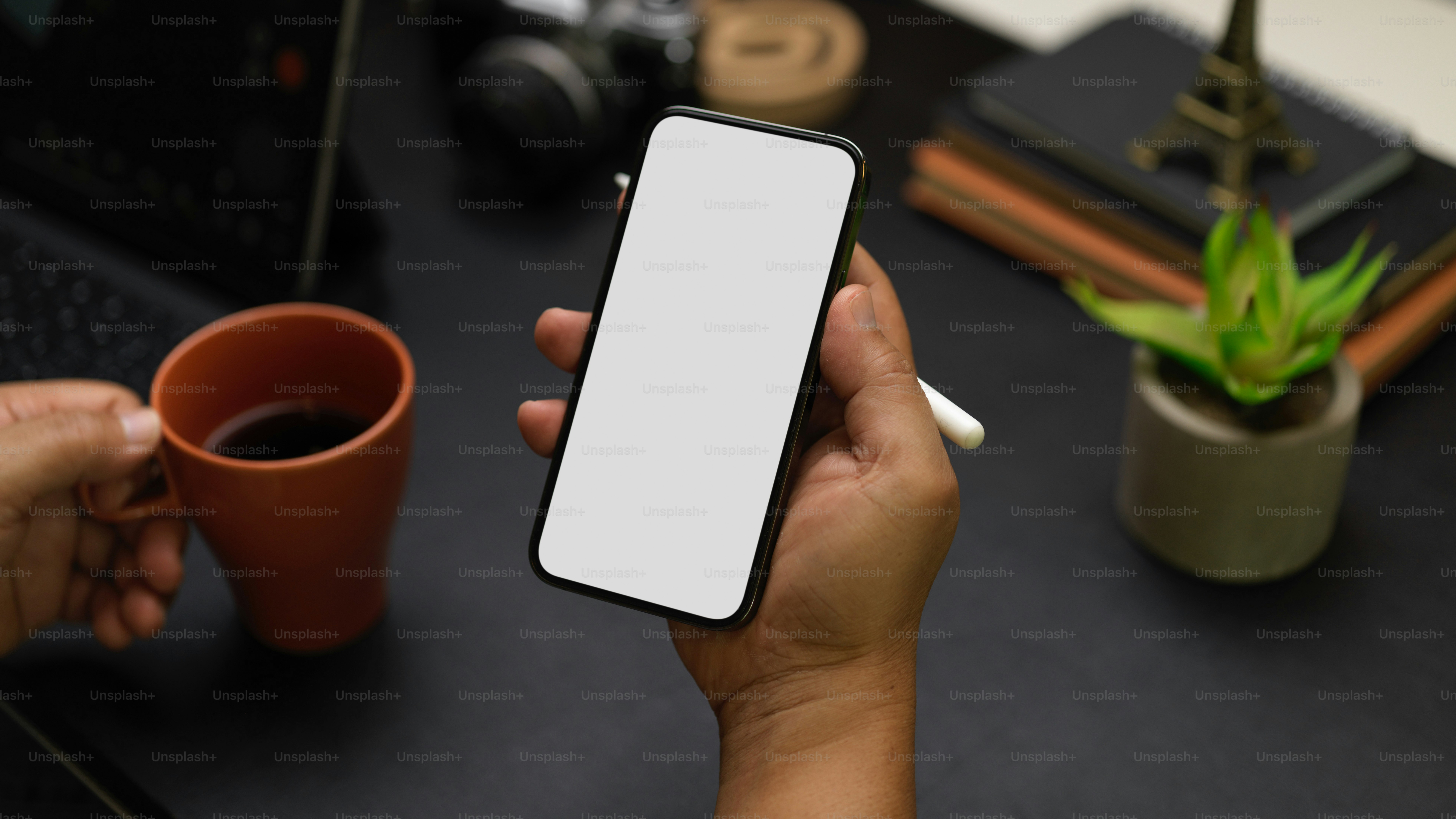 Closeup, Businessman looking on smartphone while drinking coffee for breakfast, phone screen mockup, decor on black workspace with blurred background