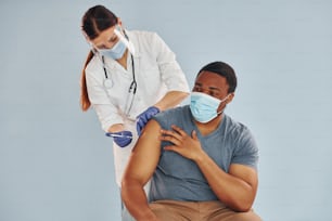 Female doctor giving injection to african american man at hospital.