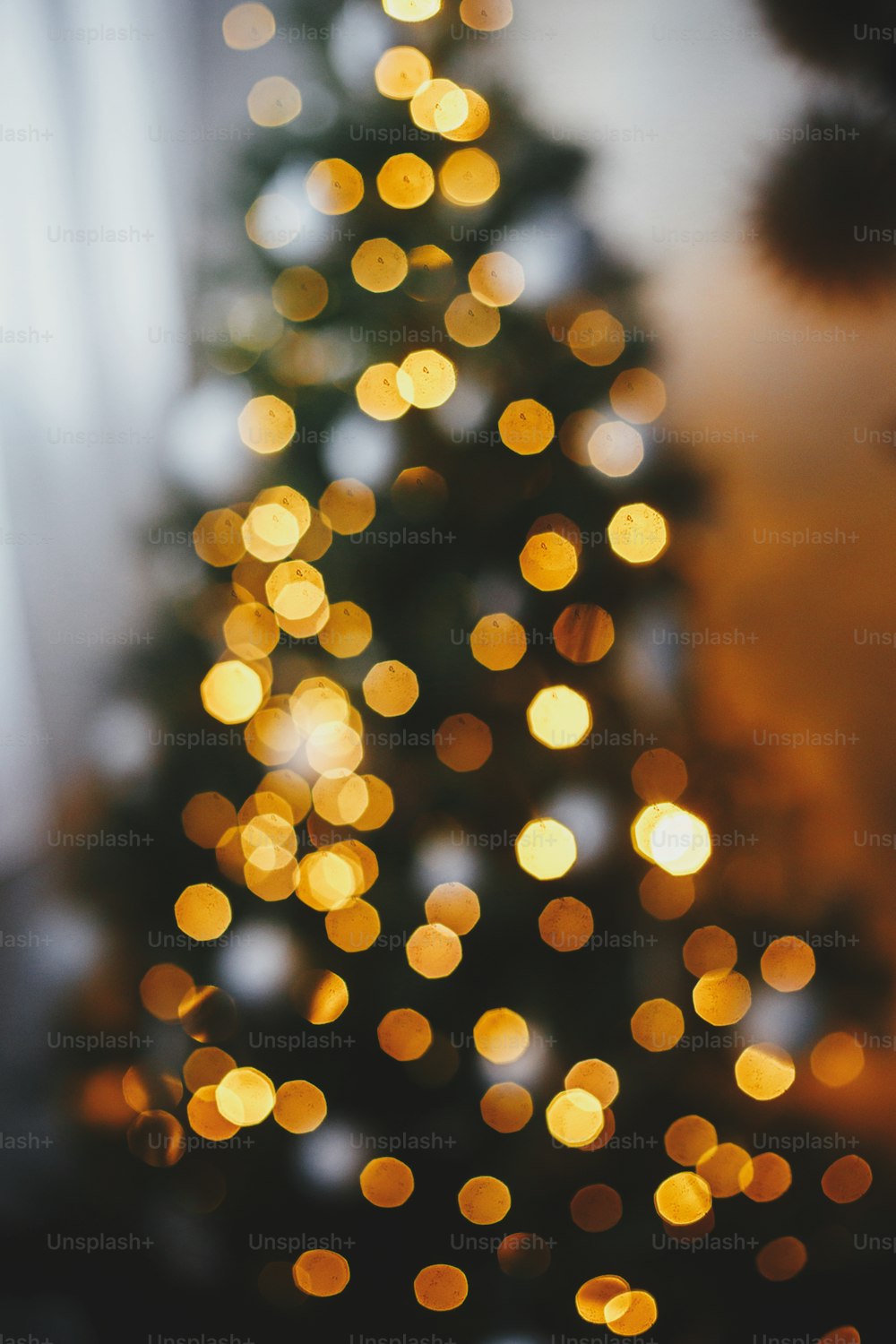 Weihnachtshintergrund. Weihnachtsbaumbeleuchtung defokussiert im abendlichen Festraum. Leuchtendes Beleuchtungsbokeh. Stimmungsvoller Heiligabend. Frohe Weihnachten und frohe Feiertage