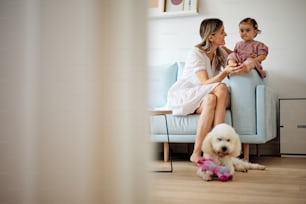 Young beautiful mother playing with her beloved baby girl at home.