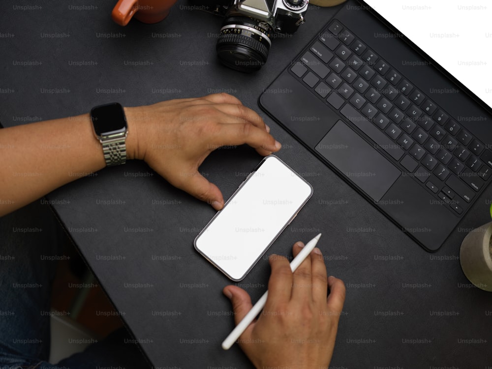 Closeup middle aged male photographer using modern mobile phone and tablet on black leather table, tablet and smartphone mockup, camera, flat lay, top view