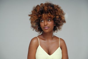 Beauty portrait of young attractive afro woman with perfect skin and delicate glamour makeup with yellow eyeliner. Girl with afro hairstyle. Studio shot. A lot of copy space.