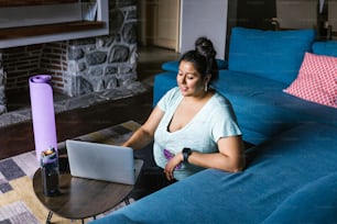 Joven mexicana de talla grande usando computadora portátil sentada en el piso en la sala de estar en América Latina