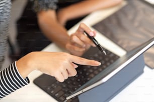 Two business worker brainstorming together, using portable tablet, pointing on screen, top view, close up