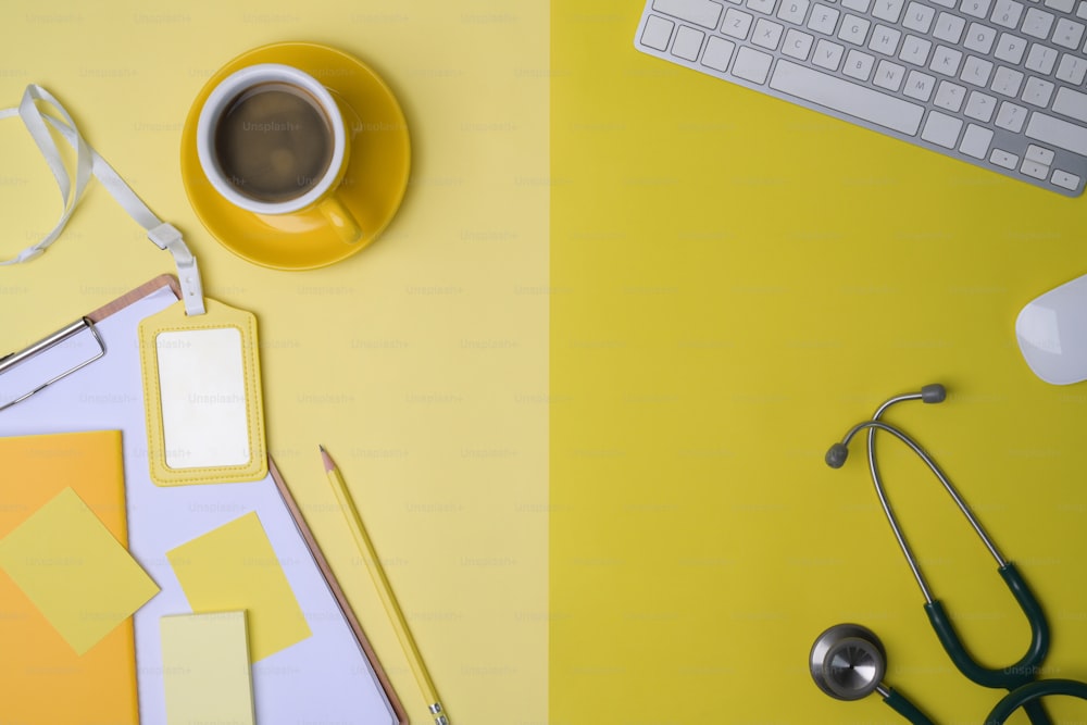 Coffee cup, stethoscope, clipboard and sticky notes on yellow background.