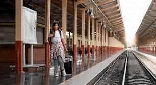 Retrato viajero mujer assian que camina y espera el tren en la plataforma del ferrocarril