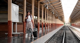 Portrait traveler assian woman walking and waits train on railway platform