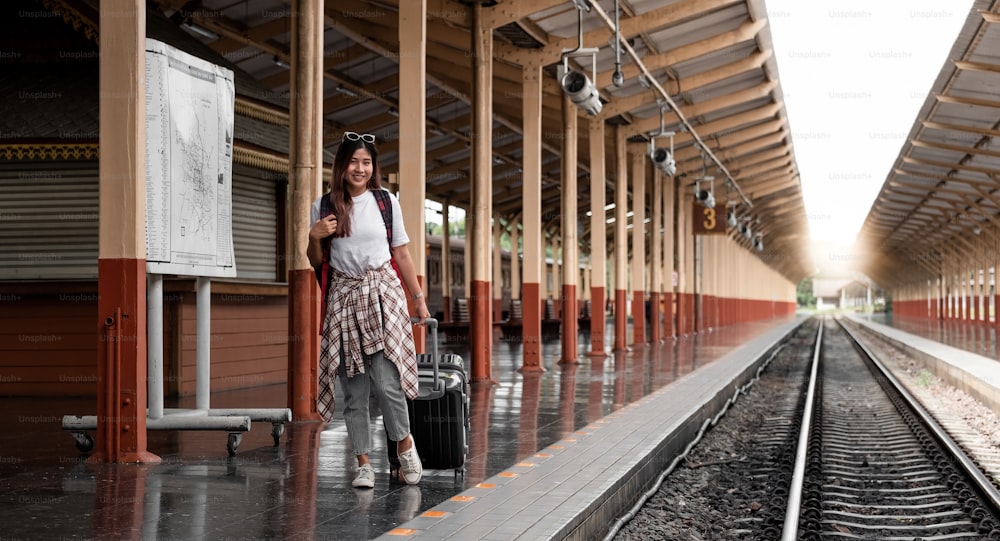 肖像画の旅行者assian女性は歩いて、鉄道のプラットホームで列車を待っています
