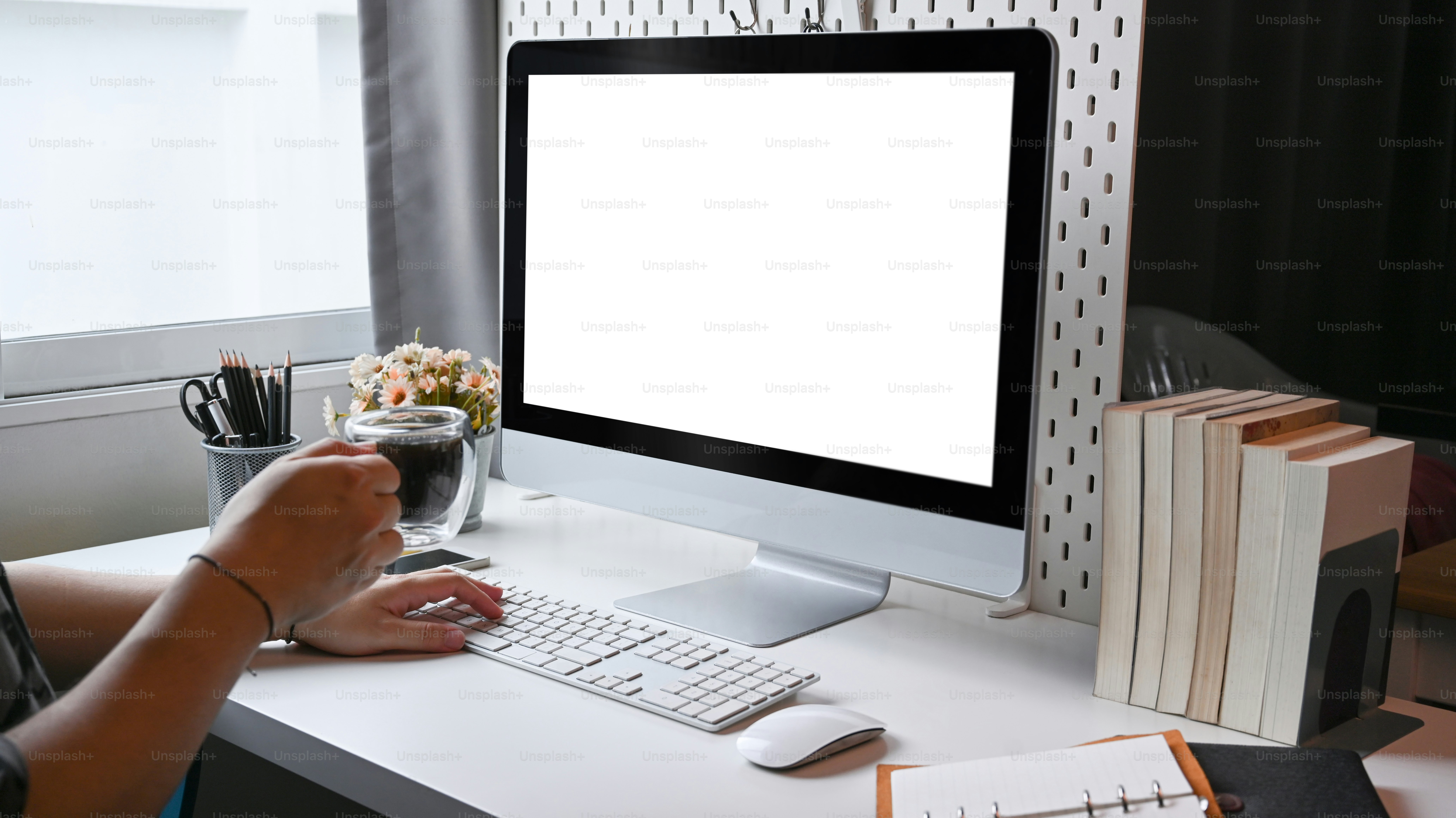 Homem segurando xícara de café e trabalhando com computador em home office.