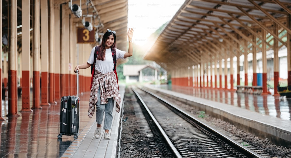 Portrait traveler assian woman walking and waits train on railway platform