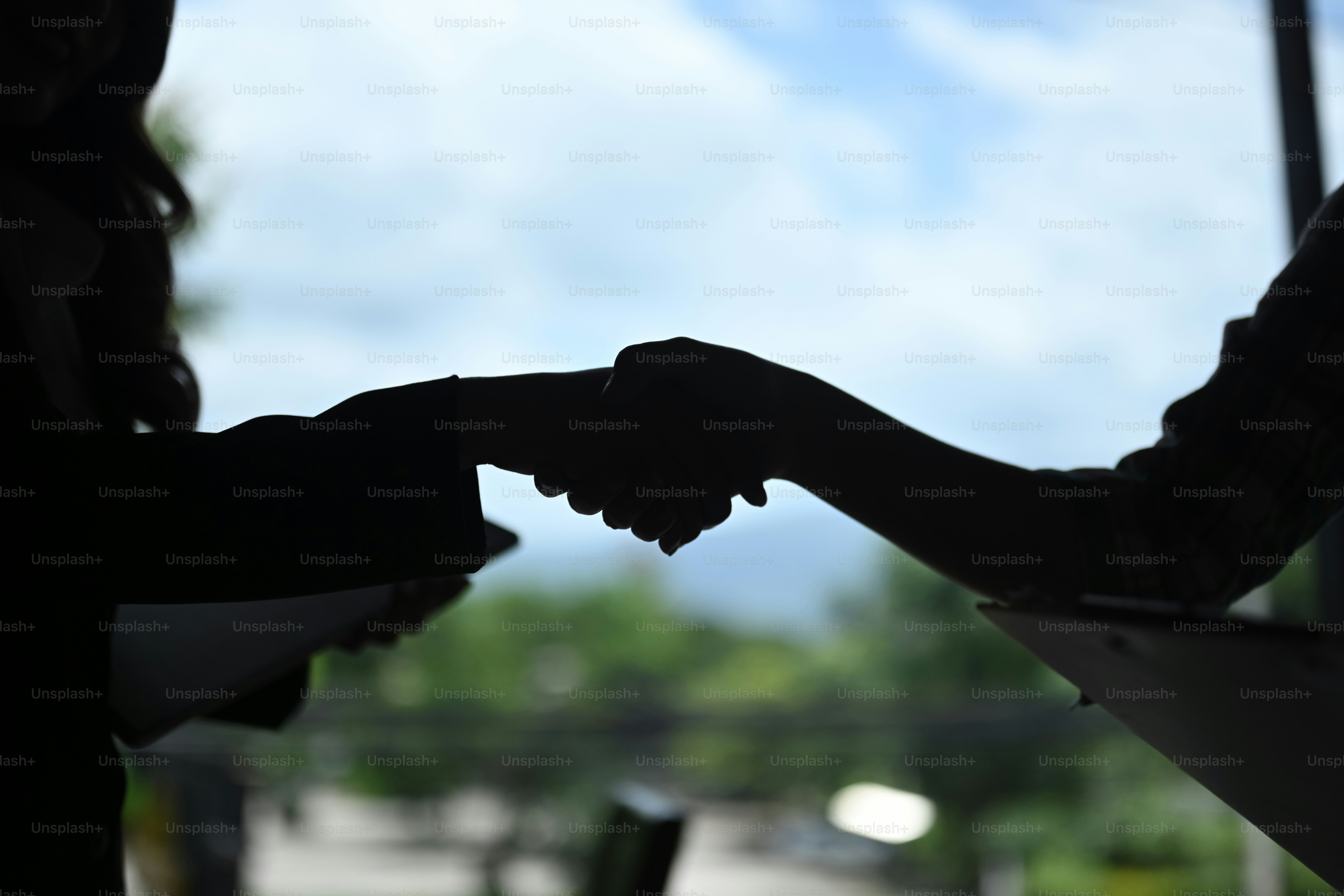 Silhouette d’hommes d’affaires se serrant la main après avoir terminé une réunion.