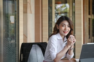 Successful business woman sitting in modern workplace and smiling to camera.