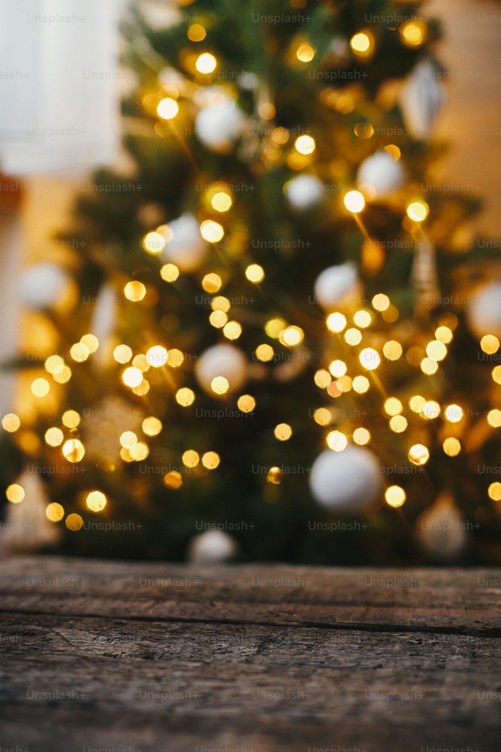 Christmas background. Rustic wood on background of christmas tree  lights golden bokeh. Space for text. Decorated tree glowing in festive scandinavian room. Atmospheric christmas eve. Happy holidays