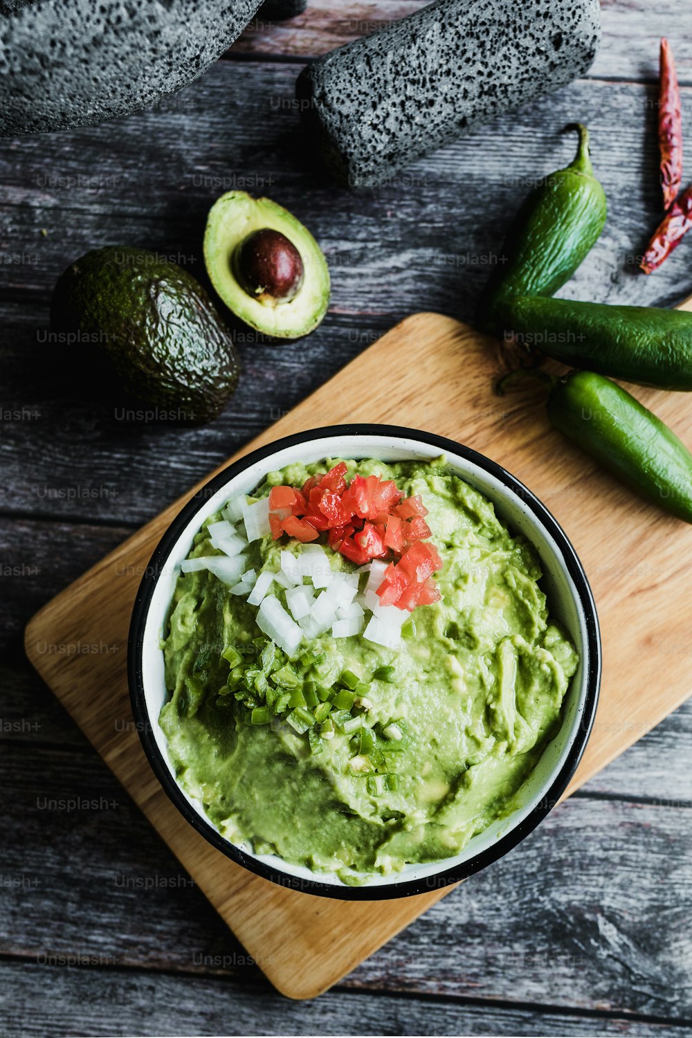 Bowl of Guacamole next to fresh ingredients on a wooden table in Mexico