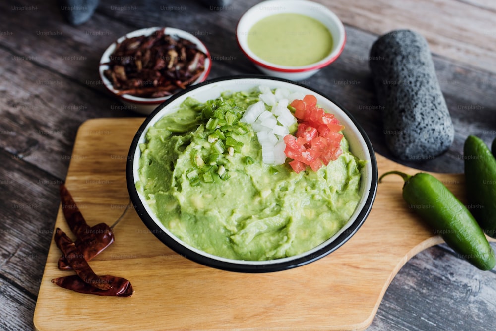 Bowl of Guacamole next to fresh ingredients on a wooden table in Mexico