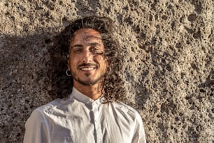 Retrato de primer plano de un hombre italiano guapo sonriente con cabello largo y rizado. Foto al aire libre.