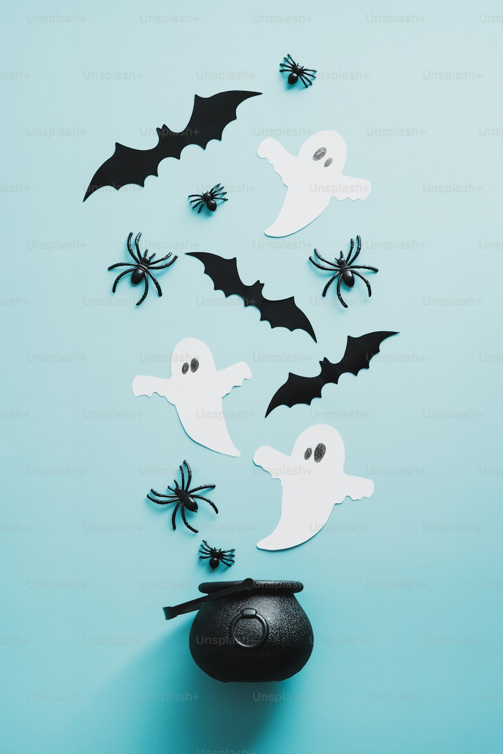 Spooky evil spirits and witch pot on blue background. Flat lay, top view spiders, paper ghosts, bats.