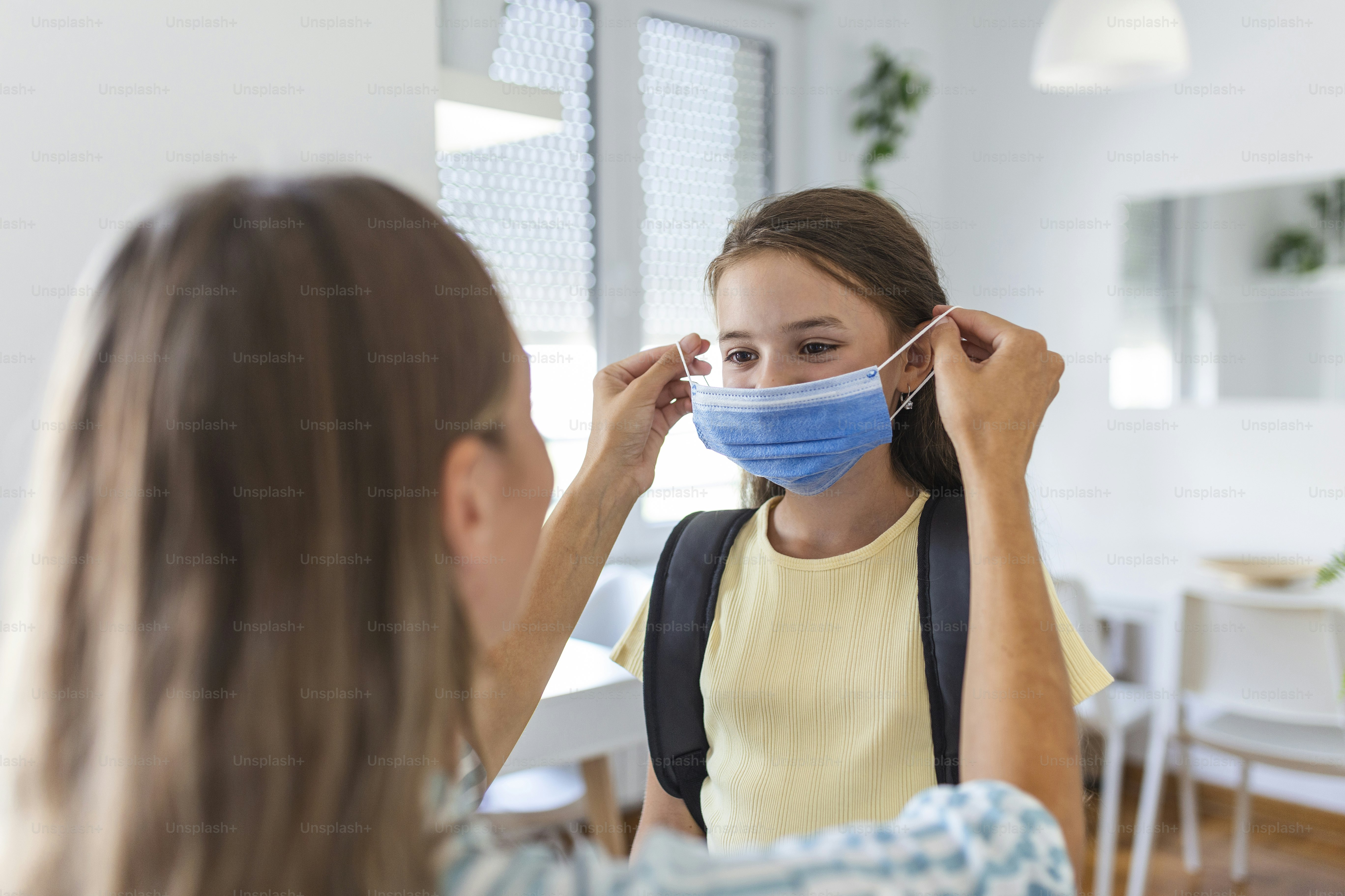 Young mother help her daughter wearing medical mask to prepare go to school. Avoiding Covid-19 or coronavirus outbreak. Back to school