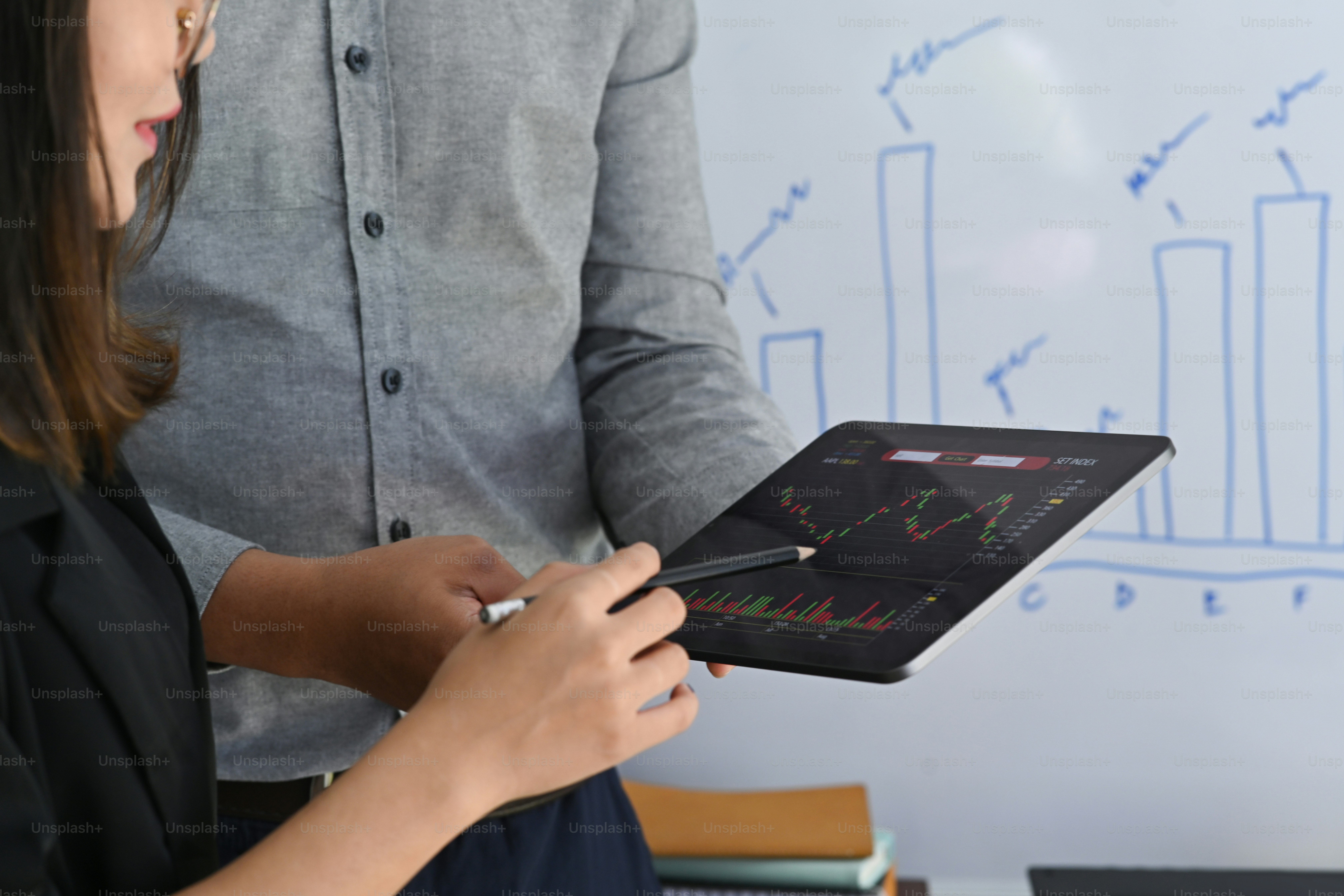Business people analyzing graph of stock market on digital tablet together.