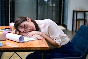 Overworked female office worker sleeping at her office desk.