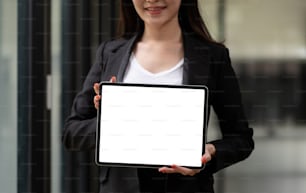Cierre en la tableta en blanco que la mujer de negocios muestra y sostiene con las dos manos, simula el espacio para la exhibición.