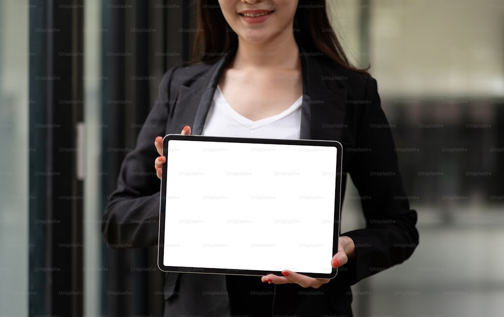 Nahaufnahme auf leerem Tablet-Computer, den Geschäftsfrau zeigen und mit zwei Händen halten, Mock-up-Platz für die Anzeige.