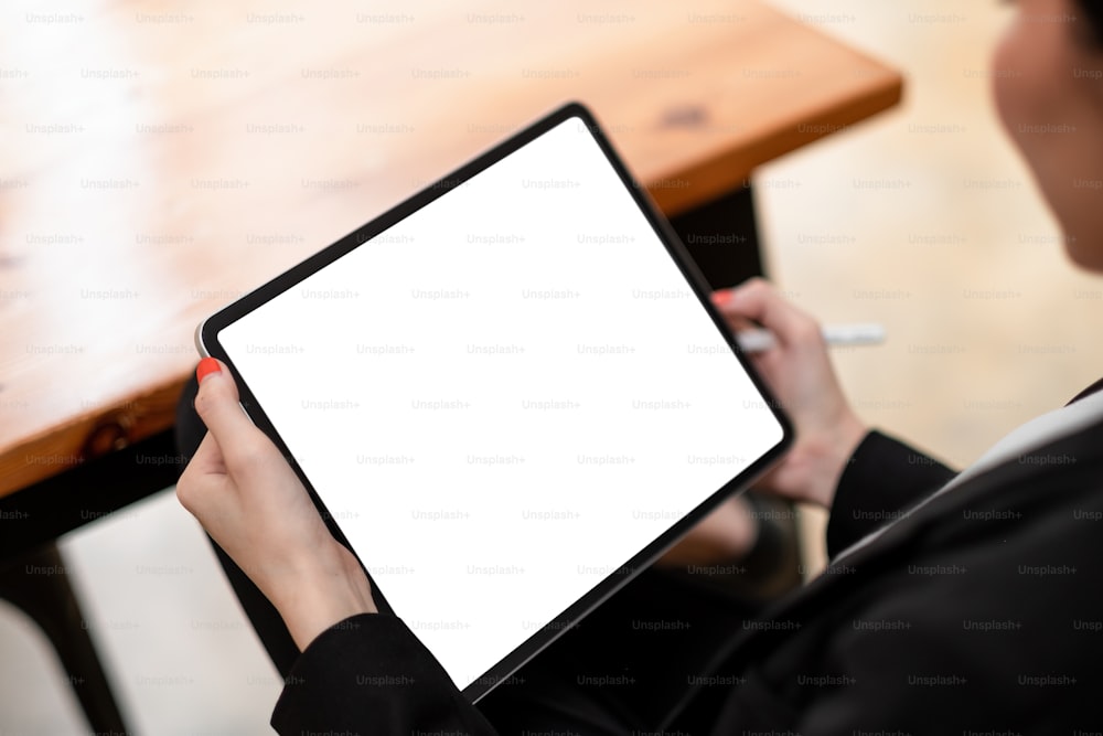 빈 흰색 화면이 있는 디지털 태블릿 PC에서 스타일러스로 작업하는 여성의 클로즈업.