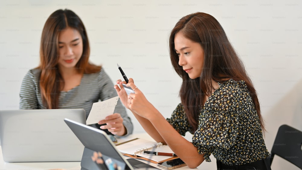 Attractive businesswoman holding credit card in workplace at office, online payment, online shopping