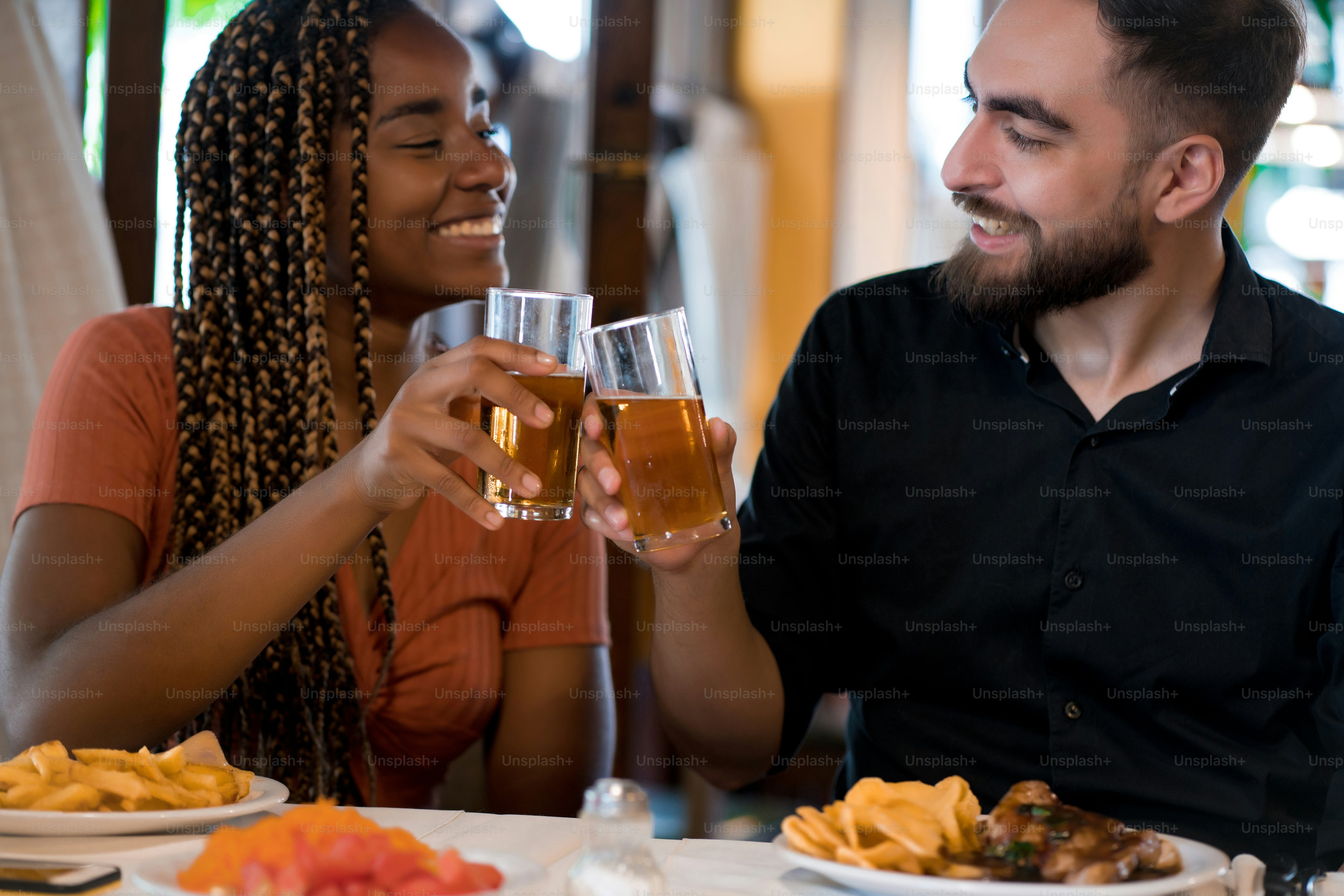 Couple eating steak together smiling and drinking