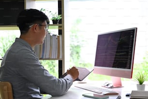 Homme d’affaires vérifiant les données boursières sur un ordinateur au bureau.